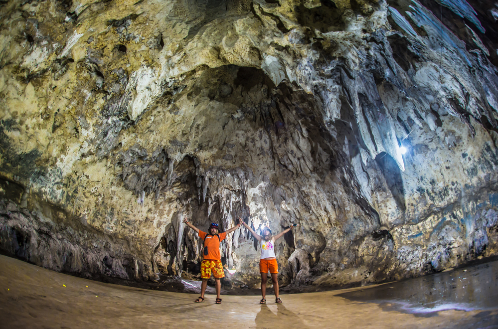 Two people having fun exploring a large cave.